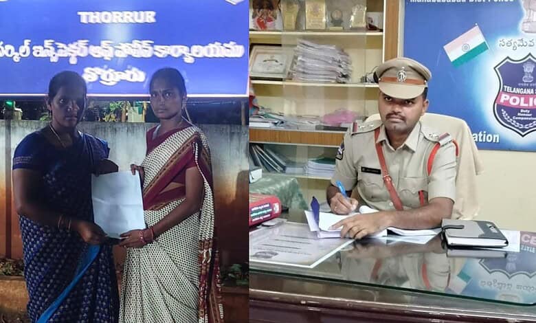 Police officer at a desk with two women in traditional attire in an office setting.