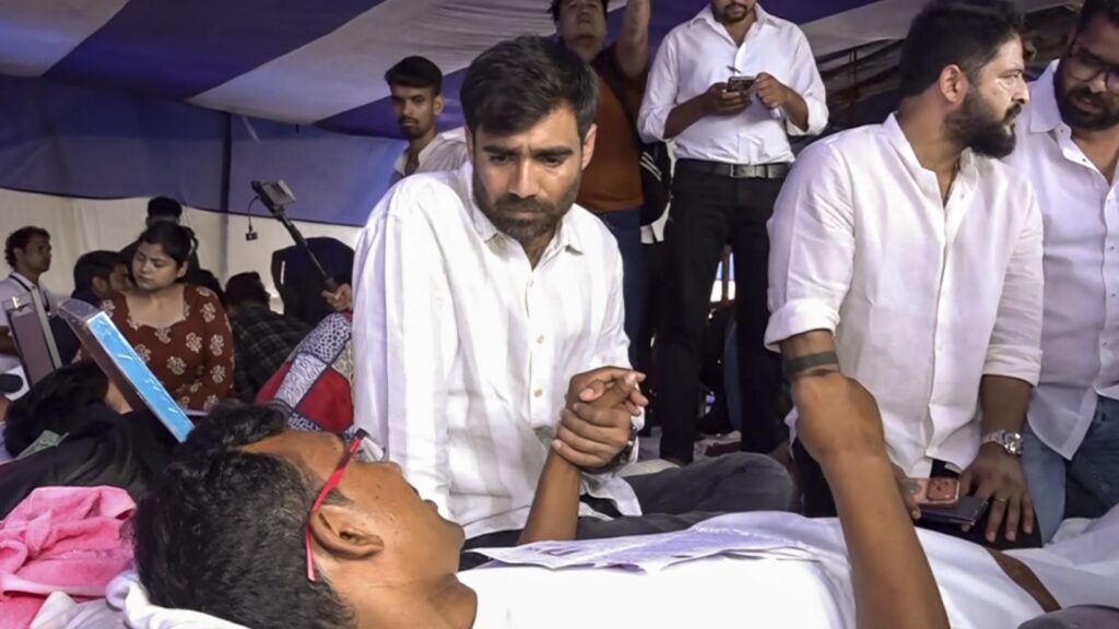 Jharkhand student protests: student lying on hospital bed with supporters around.