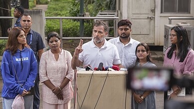 Rahul Gandhi addresses media with diverse group of supporters outdoors in India.