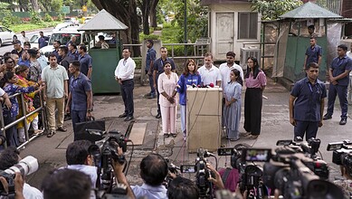 Press conference with officials and media at a public event in an outdoor setting.