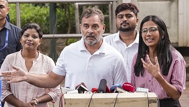 Rahul Gandhi speaking at a press conference with women supporters in the background.