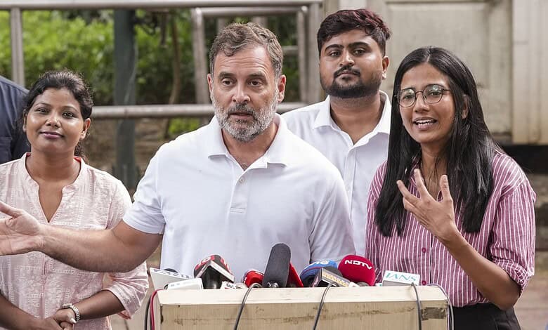 Rahul Gandhi speaking at a press conference with women supporters in the background.