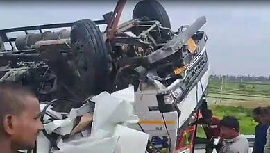 Upside-down car crash scene with people inspecting the wreckage on a greenfield NH.