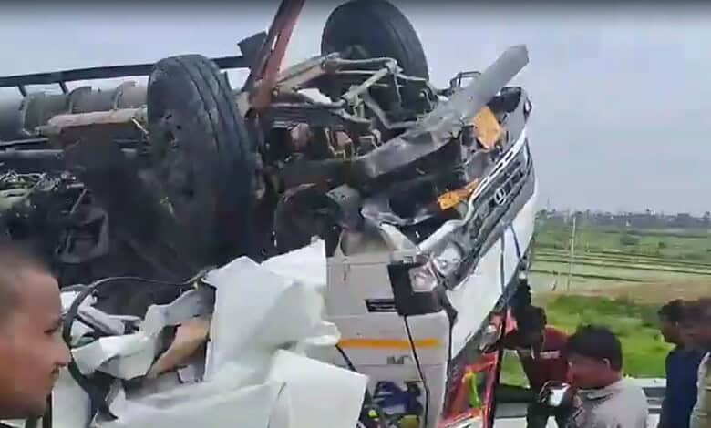 Upside-down car crash scene with people inspecting the wreckage on a greenfield NH.