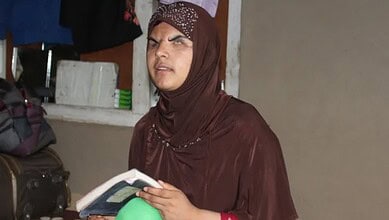 Kashmir pellet victim Insha Mushtaq reading a book indoors.