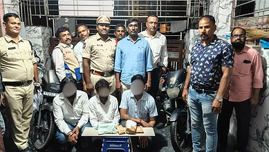 Group of police officers and civilians gathered around a table with motorcycles in Hyderabad.