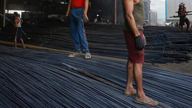 Workers inspecting steel rods at a construction site in Telangana, India.