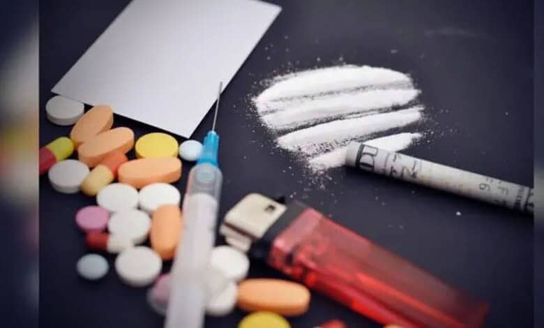 Various pills, a syringe, and a white powder on a dark surface, highlighting drug abuse issues.