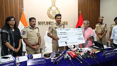 Telangana DGP Anand with officials and Maoists during Mulugu interaction, holding a cheque.