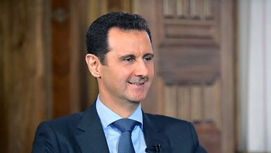 Syrian President Bashar al-Assad smiling during a formal event or interview.