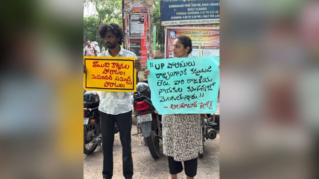 Two protesters holding signs in Telugu during a demonstration in Hyderabad, India.