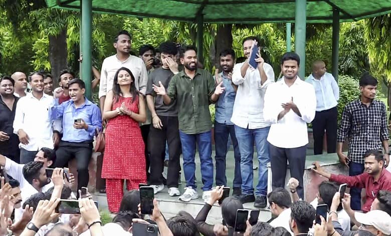 Group of people gathered outdoors at a public event, some taking photos and videos.