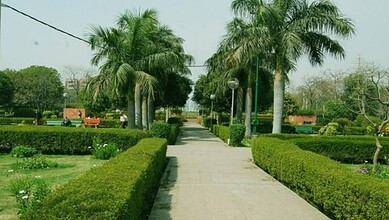 Well-maintained park with palm trees, benches, and a paved walkway in Medchal.