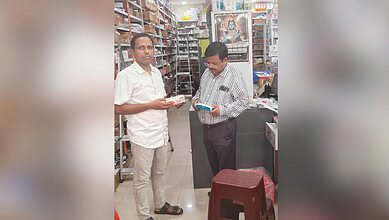 Two men in a pharmacy discussing weight loss drugs, shelves filled with medicines in the background.