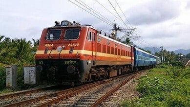 Electric train moving through lush green landscape near Hi-Tec City station during Dasara.