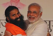 Prime Minister Narendra Modi embracing yoga guru Ramdev at a public event.