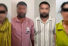 Four individuals with blurred faces standing indoors, three men and one woman, in casual attire.