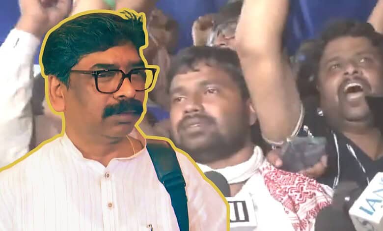 Man with glasses and mustache at a protest or rally, surrounded by crowd members.