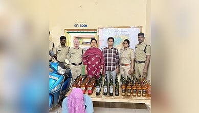 Telangana exise officials with the arrested man and seized liqour