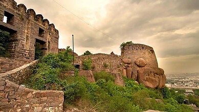Ancient stone fortification at Golconda Fort with a cloudy sky in the background.