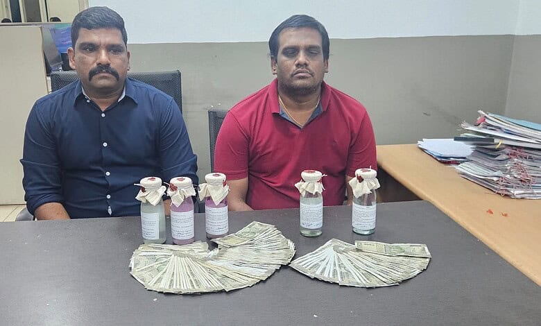 Two men seated at a table with confiscated drugs and cash displayed in front of them.