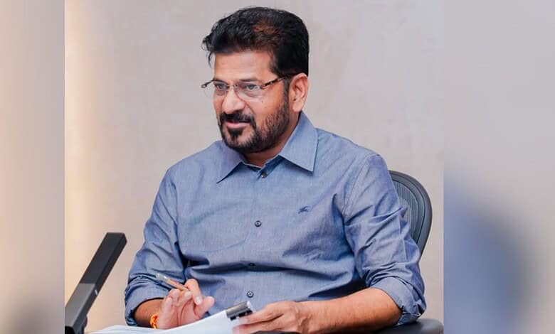 Revanth during a meeting, wearing a blue shirt and glasses, in an office setting.