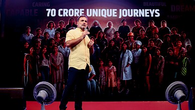 Rahul Gandhi speaking at a public event with a large crowd behind him.