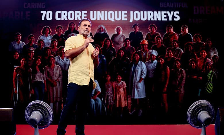 Rahul Gandhi speaking at a public event with a large crowd behind him.