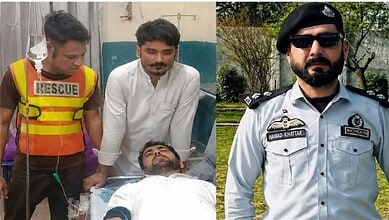 Security personnel and a doctor attending to a wounded man in a hospital bed.