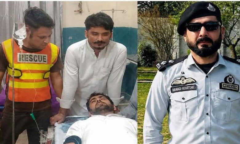 Security personnel and a doctor attending to a wounded man in a hospital bed.