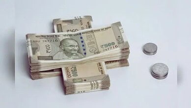 Stacks of Indian 500 rupee notes and coins on a white surface.