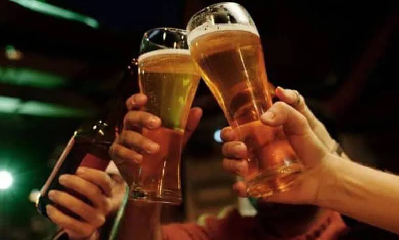 People holding glasses of beer in a social setting at night.