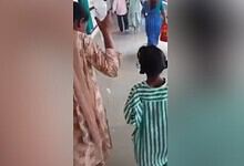 Woman holds daughter's saline bottle at MGM Hospital in Warangal, India.