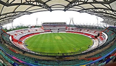 Uppal cricket stadium with empty stands and green pitch under a large roof structure.