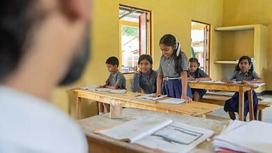 Young students in a classroom with yellow walls and open windows, engaged in learning activities.