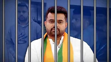 Prajwal Revanna behind prison bars, looking serious and contemplative.