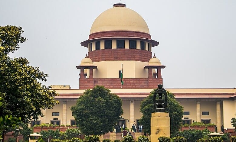 Supreme Court building in India with a statue in front and lush greenery around.