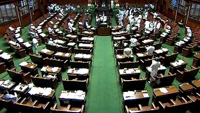 Karnataka Assembly session with members seated in a semi-circular arrangement.