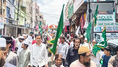 Crowd participating in Milad-un-Nabi procession in Hyderabad with flags and banners.