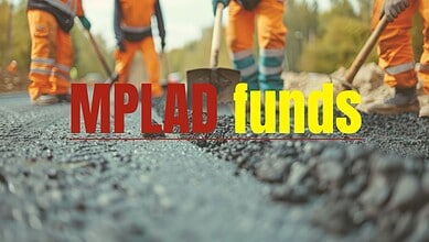 Workers laying asphalt on a road with MPLAD funds text overlay.