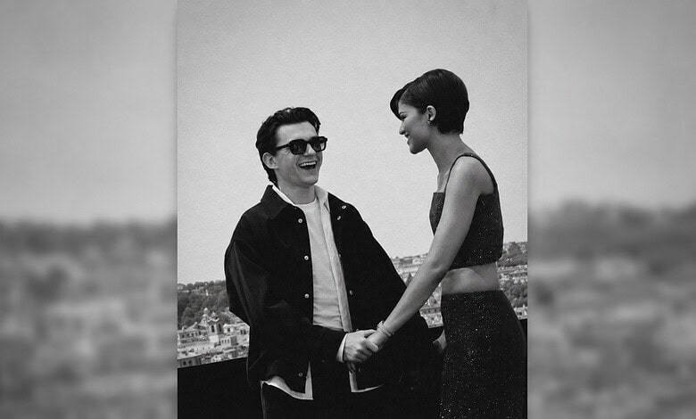 A smiling man and woman holding hands outdoors, with a cityscape in the background.