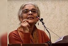 JNU professor speaking passionately at a podium during a speech event.