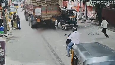 Accident scene in Hyderabad with a motorcycle under a truck and bystanders nearby.