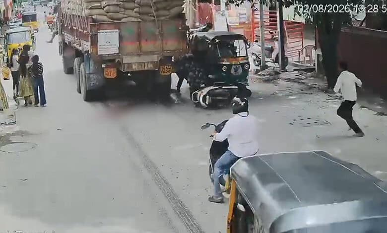 Accident scene in Hyderabad with a motorcycle under a truck and bystanders nearby.
