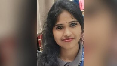 Close-up of a young woman with black hair and a bindi, smiling at the camera.