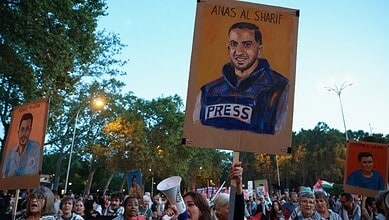 Protesters in Gaza hold signs, including a portrait of journalist Anas Al-Sharif, during a demonstration.