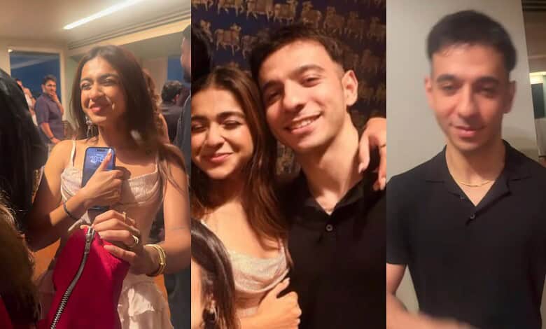 Young woman smiling and taking a selfie at an indoor event with friends.