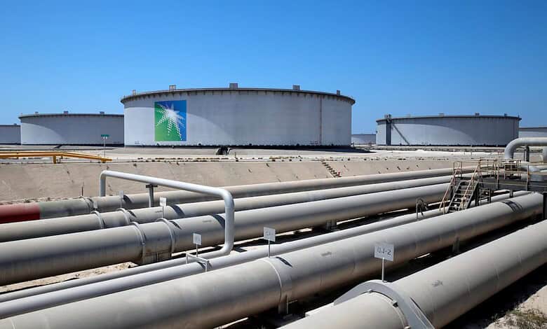 Large storage tanks at Saudi Aramco refinery under clear blue sky.