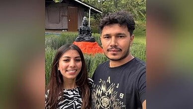 Young couple taking a selfie outdoors with a Buddha statue in the background.