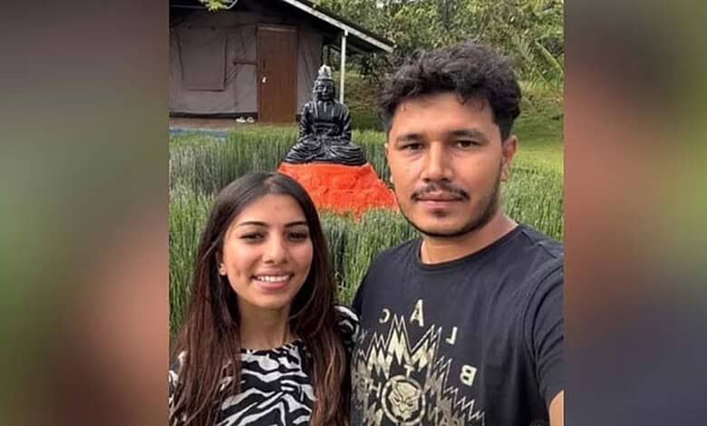 Young couple taking a selfie outdoors with a Buddha statue in the background.